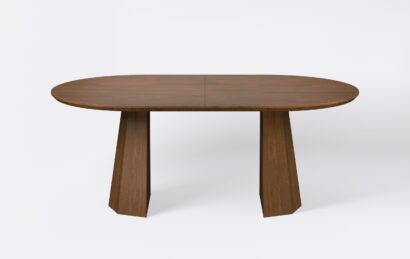 Owalny stół z funkcja rozkładania, na dwóch nogach, fornirowany, o wybarwieniu ciemnego dębu.